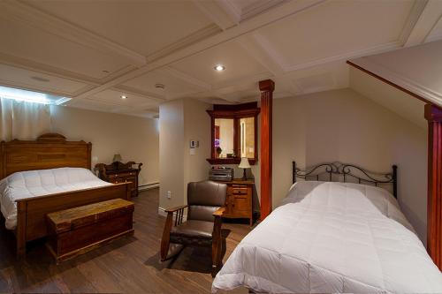 a bedroom with two beds and a desk and a chair at Auberge Mr James in Rivière-du-Loup
