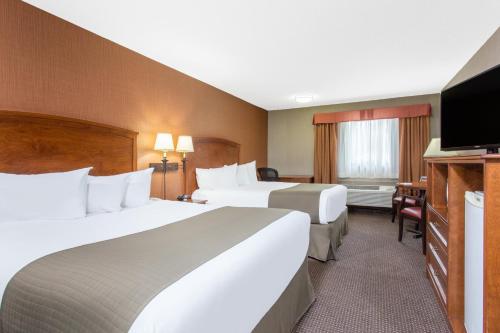 a hotel room with two beds and a flat screen tv at Canmore Inn & Suites in Canmore