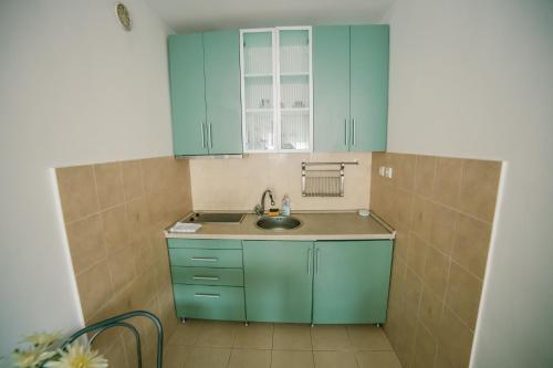 uma pequena cozinha com armários azuis e um lavatório em Apartment Stela em Belgrado