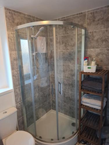 a shower with a glass enclosure in a bathroom at Cheerful 3 bedroom house with free parking in Hurlet