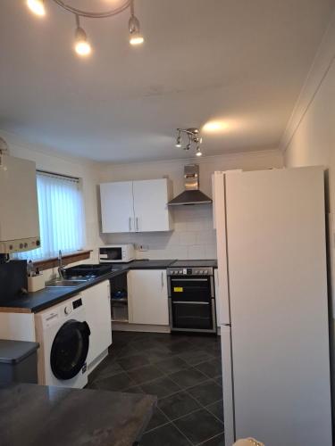 a kitchen with white appliances and a white refrigerator at Cheerful 3 bedroom house with free parking in Hurlet