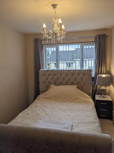 a bedroom with a bed with a chandelier and a window at Cheerful 3 bedroom house with free parking in Hurlet