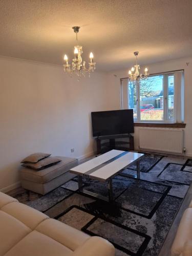 a living room with a couch and a table at Cheerful 3 bedroom house with free parking in Hurlet