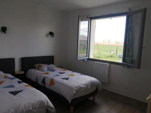 two beds in a room with a window at Le clos des vaches in Usson-du-Poitou
