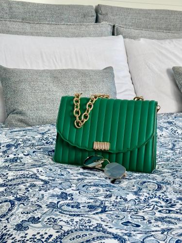 a green purse and chain on a bed at Aurora View Resort - Boutique Suites in Mascali