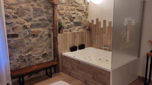 a bathroom with a tub and a stone wall at Casa rural Abatetxe in Elgóibar