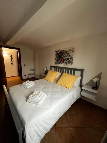 a bedroom with a large white bed with yellow pillows at Casa San Pietro centro storico in Castagnole Lanze