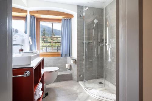 a bathroom with a shower and a toilet and a sink at Hôtel Bodenhaus in Splügen