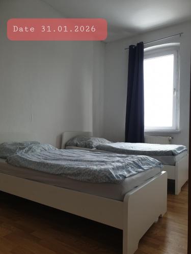two beds in a room with a window at Monteurwohnung bei Nina in Zeitz