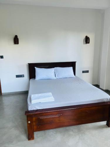 a bed with a wooden frame and white sheets at Mama Place in Hikkaduwa
