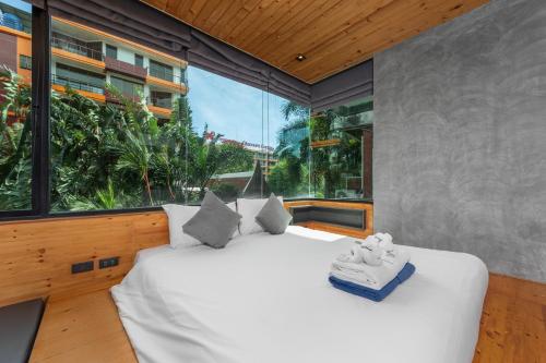 a bedroom with a large bed and a large window at Relife Apartments by Tropiclook - Fast WiFi , Pool and Gym in Phuket