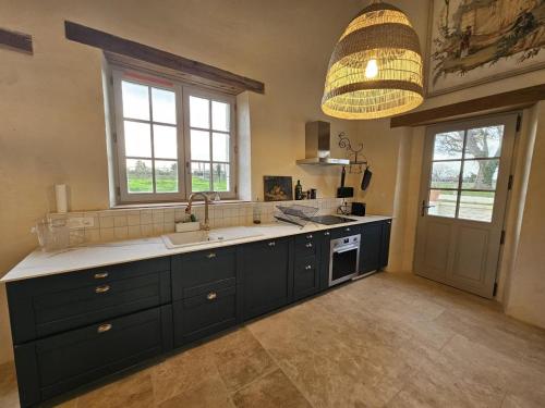 a kitchen with black cabinets and a sink and a chandelier at Gîte de la petite touche in Seligny