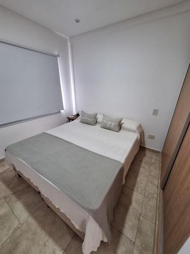 a white bedroom with a large bed with a window at Artigas 505 dpto 2 in Colón