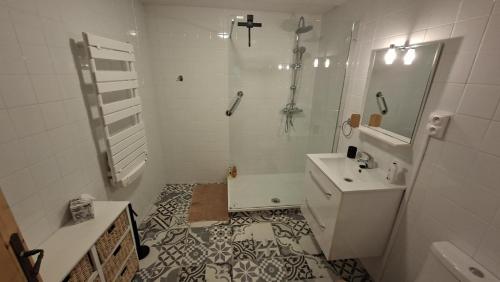 a white bathroom with a shower and a sink at Émeraude in Voulême