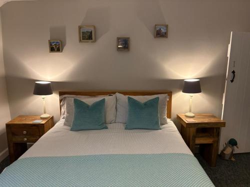 a bedroom with a bed with blue pillows and two lamps at Blue Sky Cottage in Matlock