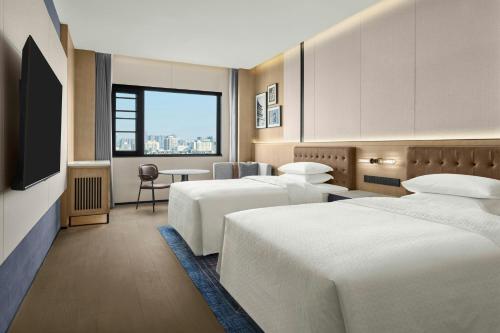 a hotel room with two beds and a television at Four Points by Sheraton Xi'an Bell Tower in Xi'an
