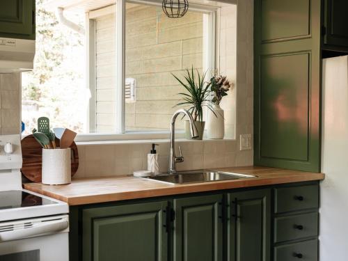 a kitchen with green cabinets and a sink and a window at Chalet rustique, Lac paisible, Canot, Famille in La Conception