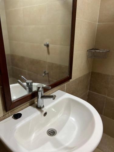 a white sink in a bathroom with a mirror at GREENFIELD STUDlO DONHOLM in Nairobi