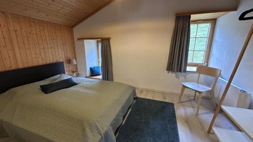 a bedroom with a bed and a chair and a window at Tgesa communala Mon in Mons