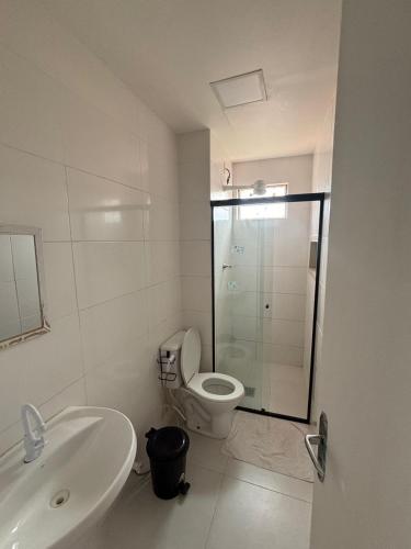 a white bathroom with a toilet and a sink at Apartamento no centro de Cuiaba até 3 pessoas in Cuiabá