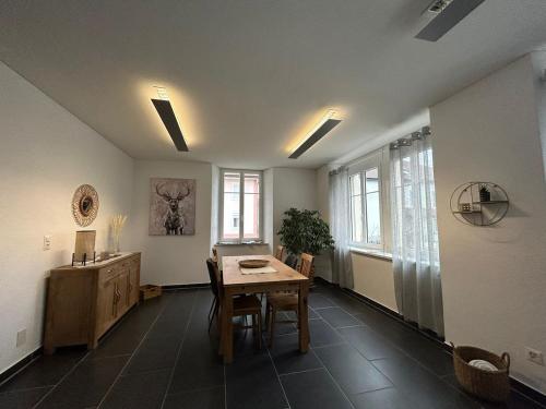 a room with a table and a desk and some windows at Appartement Atelier in Le Noirmont