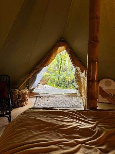 a tent with a bed in a room with a window at Le Moulin de Trévelo in Caden