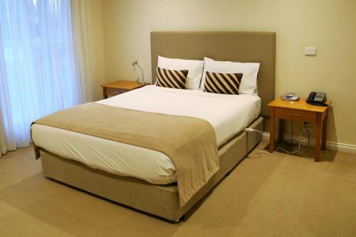ein Schlafzimmer mit einem großen Bett mit zwei Nachttischen in der Unterkunft Allansford Hotel Motel in Allansford