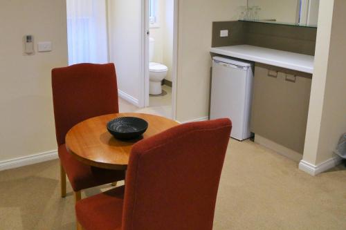 cocina con mesa, sillas y fregadero en Allansford Hotel Motel, en Allansford