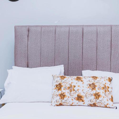 a bed with two pillows and a headboard at Bethany Cushy Home Ltd in Kisii
