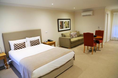 a hotel room with a large bed and a couch at Allansford Hotel Motel in Allansford