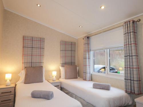 two beds in a room with a window at Iona Lodge in Fort William