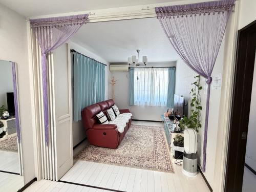 a living room with a red couch and purple curtains at sakuraの家 in Tokyo