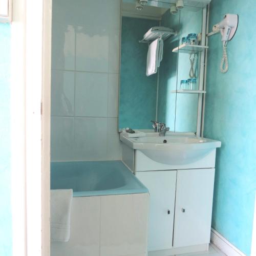 a white bathroom with a sink and a mirror at Hotel Au Petit Béarn in Salies-de-Béarn