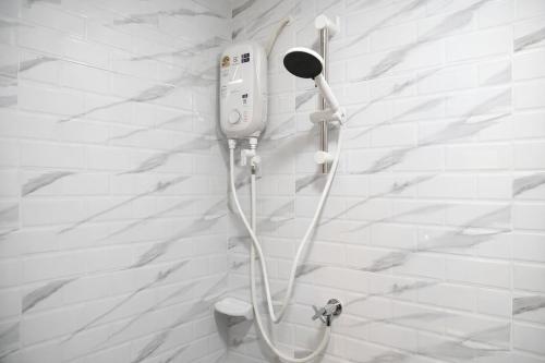 a shower in a bathroom with a white wall at Family Hostel in Chiang Rai
