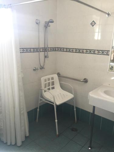 a bathroom with a shower and a chair in it at Abel Tasman Motor Inn in Dubbo