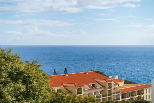 a building with an orange roof next to the ocean at Lido Mar - Hotels area in Funchal