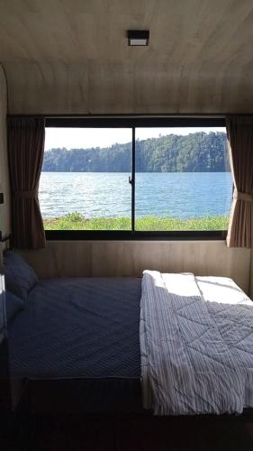 a bedroom with a window looking out at the water at ARA Caravan Villa in Bedugul
