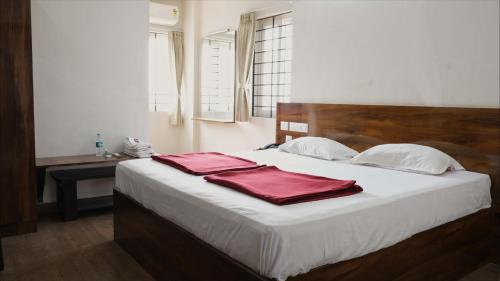 a bedroom with a bed with two red towels on it at Rams Inn in Krishnagiri