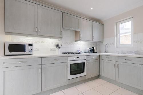 a white kitchen with white cabinets and a microwave at Roomspace Serviced Apartments - Cascades Court in London