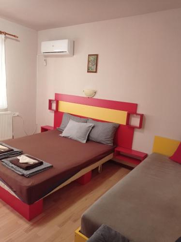 a bedroom with a bed with a red and yellow headboard at Chergata Guest House in Zheglitsa