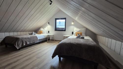 a attic bedroom with two beds and a table at Domek na Ogrodowej in Tylicz