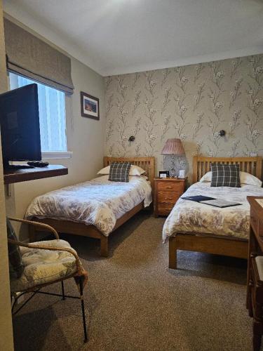 a bedroom with two beds and a flat screen tv at Whitecroft B&B in Edinburgh