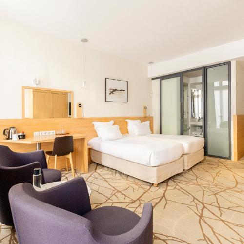 a bedroom with a bed and two chairs and a desk at Grand Hotel Francais in Bordeaux