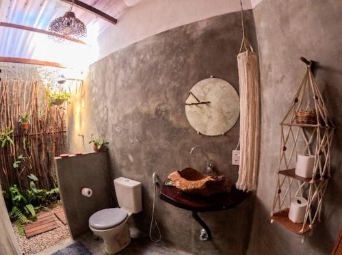 a bathroom with a toilet and a clock on the wall at Casa do Francês in Japaratinga