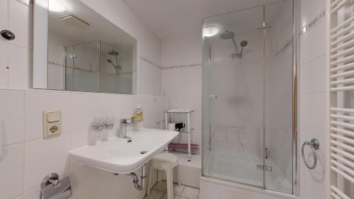 a white bathroom with a sink and a shower at FeWo direkt am Strand , mit Balkon und seitlichem Meerblick, Haus Strelasund, Binz in Binz