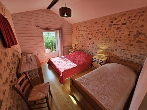 a bedroom with two beds and a table and a window at Gîte de la vacherie in Port de Salles