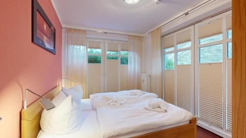 a bedroom with a bed with white sheets and windows at strandnahe FeWo mit 2 Schlafzimmern und Terrasse oder Balkon, Caspar David, Binz in Binz