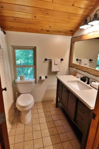 a bathroom with a toilet and a sink and a mirror at The Highland in Cherokee