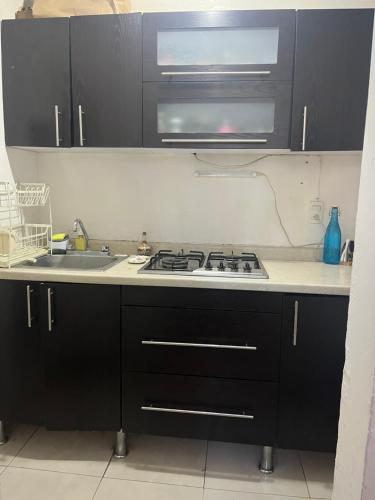 a kitchen with black cabinets and a stove top oven at Cuarto cómodo y económico cerca Expo GDL Plaza Sol in Guadalajara