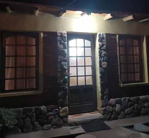 a front door of a house with two windows at El Volcán in Tupungato